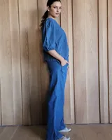 Conjunto de camisa y pantalón de lino blanco. La camisa es de manga larga y se ata en la parte delantera. El pantalón es de corte ancho y tiene cordón en la cintura.