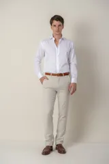 Pantalón de vestir color beige, de corte clásico, con bolsillos laterales y traseros. Se ajusta a la cintura con cinturón de cuero marrón.