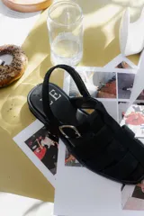 Sandalias de cuero marrón con diseño de tiras entretejidas y hebilla lateral.