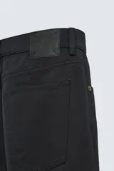 Pantalón de jean negro de corte recto, con cinco bolsillos y cierre frontal con botones. Colección especial Origins.
