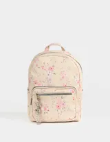 Mochila urbana negra de cuerina con bolsillo frontal con cierre y charm colgante de cadena con dije de corazón y candado. Tiene correas regulables, manija superior, cierre superior, doble bolsillo frontal (uno con charm metálico) y bolsillos laterales.