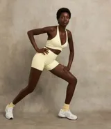 Top deportivo frente única confeccionado en microfibra color crema, con escote en V cruzado y copas removibles.