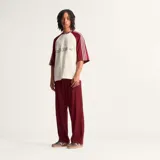 Camiseta Adidas Originals color crema con mangas ranglán color borgoña y tres tiras blancas en los hombros. Logotipo de Adidas bordado en el pecho. Corte oversize.