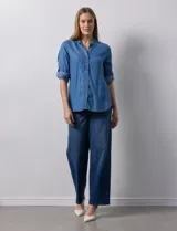 Camisa celeste de tencel con cuello con solapa, escote en V, abertura central con botones y mangas 3/4 regulables con presilla y botón.