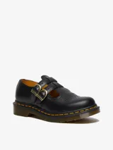 Zapato Mary Jane Dr. Martens modelo 8065, color negro, con doble correa con hebillas doradas, detalles brogue en la puntera y suela con costuras amarillas.