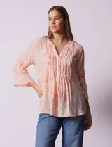 Blusa de gasa estampada color salmón con flores blancas, marca Ruby Rd. Cuello a la base, escote en V y abertura central con botones. Delantera con plisados. Largo de manga ¾ con terminación amplia.
