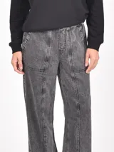 Pantalón de mezclilla ancho color verde oliva desgastado, con cintura elástica y costuras verticales marcadas en el frente de cada pierna.