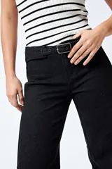 Pantalón de jean azul oscuro, de corte flare con cinturón incorporado en la misma tela y silueta ajustada en cadera que se ensancha hacia el ruedo.