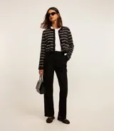 Pantalón de vestir negro de corte wide leg, confeccionado en crepé. Presenta cintura con trabillas, detalle de solapa con botón y bolsillos laterales.