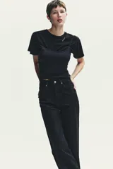Pantalón de jean azul oscuro, de tiro alto, corte wide leg y largo hasta el tobillo.