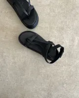 Sandalias de cuero vacuno color negro, con tiras finas y suela plana.