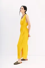 Vestido largo color amarillo mostaza, con escote en V, sin mangas y cintura elastizada con lazo.