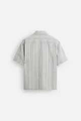 Camisa de manga corta con cuello bowling y corte relaxed fit, confeccionada en tejido con algodón y diseño a rayas verticales en tonos beige y blanco.
