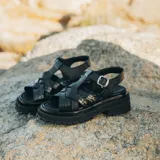 Sandalias bajas de cuero vacuno color beige con tiras cruzadas plateadas y hebilla lateral. Suela doble de goma deportiva con altura de 3cm adelante y 5,5cm atrás.