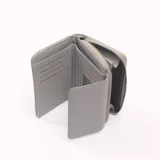 Billetera gris con cierre de cremallera y solapa con broche a presión.