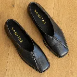 Zapato bajo de cuero negro con punta cuadrada y detalle de cierre en la capellada.