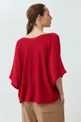 Sweater de punto color rojo, con diseño oversized, escote en V y mangas anchas de estilo murciélago.