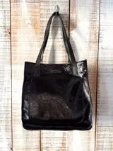 Bolso tipo tote de cuero, color marrón oscuro con efecto desgastado o envejecido, con asas cortas y correa larga ajustable para llevar al hombro o cruzado. Presenta un bolsillo exterior frontal grande con solapa.