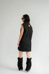 Vestido corto de jean gris con botones frontales, sin mangas, con cuello camisero y bolsillos en el pecho.