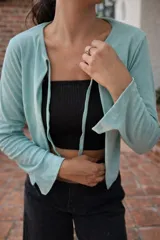 Saco de tejido ligero color beige, de manga larga y corte abierto, con cuello redondo.