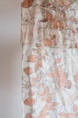 Pañuelo rectangular de seda color crema con estampado botánico en tonos naranja y marrón, realizado con hojas de eucalipto y casuarina.