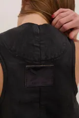 Chaleco negro de denim con proceso de encuerado, tres botones y dos bolsillos grandes laterales.