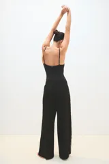 Pantalón palazzo negro con cintura elástica y una fina línea blanca vertical en los laterales.