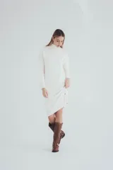 Vestido corto tejido de punto color crema, con cuello alto y mangas largas.