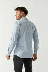 Camisa de hombre a rayas verticales celestes y blancas, corte slim fit, manga larga, logo bordado en el pecho y cartera con botones.