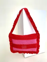Cartera tejida a crochet con hilo 100% de algodón, diseño a rayas horizontales rojas y rosadas, con volados en los bordes y manija.