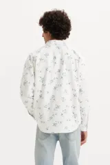 Camisa de hombre de corte relajado, color blanco con estampado floral azul, con cuello clásico, cierre con botones a presión, mangas largas con puños abotonados y dos bolsillos con solapa abotonada en el pecho.