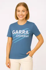 Remera celeste con estampado frontal de la frase "Garra Charrúa" en letras blancas y azules.