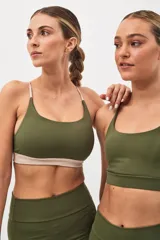 Top deportivo color beige con banda inferior azul y tirantes finos azul marino. Espalda cruzada con doble tira.