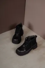 Borcegos negros de cuero charol, con punta cuadrada, cordones y suela track.