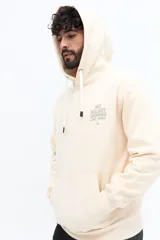 Canguro color crema claro con capucha ajustable y bolsillo canguro frontal. Presenta un estampado pequeño en el pecho con texto que dice "ART GALLERY ARCHIVES No. 1971 / TORINO".