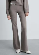 Pantalón acampanado color gris topo, de tejido de punto con cintura elástica y tiro medio.