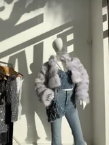 Chaqueta corta de piel sintética color gris con cuello alto y cierre metálico.