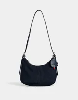 Bandolera de denim azul oscuro con correa de cuero ajustable y charm colgante en forma de corazón.