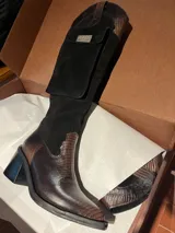 Bota de caña alta en negro y marrón, con punta y taco, equipada con un bolsillo lateral para celular.