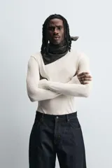 Camiseta de manga larga color crudo, corte ajustado y cuello redondo. Tiene aberturas en los puños y efecto lavado.