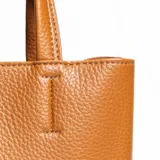 Cartera mediana color habano, de símil cuero, con doble asa corta y correa larga regulable y desmontable. Tiene acceso abierto, dos compartimentos y un bolsillo interno con cierre.