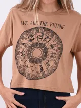 Remera corta de manga corta color marrón claro con un estampado circular de astrología y la frase "WE ARE THE FUTURE" en negro.