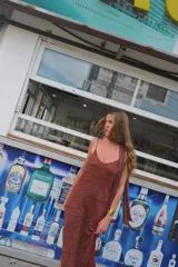 Vestido largo de tejido de punto, color terracota con brillo sutil, corte recto y escote en V. Presenta breteles finos regulables y tajo pequeño a los costados.