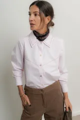 Camisa rosa pálido de algodón con cuello tipo masculino, abotonadura central, manga larga y puños con botones. Presenta canesú y cuello bordado con cadeneta a contratono.
