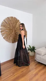 Vestido largo negro de tejido de punto con escote recto y breteles finos. La falda es de encaje transparente. Incluye una bufanda fina al tono.