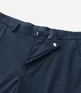 Pantalón de vestir gris claro con textura, de corte recto, con bolsillos laterales y traseros. Se ajusta a la cintura con cinturón de cuero negro.