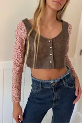 Top negro de cuero con mangas largas de encaje, escote en V y cierre frontal con botones metálicos.