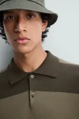 Polo relaxed fit de punto tejido en hilatura de algodón, a rayas horizontales en tonos azul y negro. Cuello solapa con cierre frontal de botonadura, manga larga y acabados en rib.