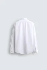 Camisa celeste de corte regular, con cuello italiano, mangas largas con puños abotonados y cierre frontal con botones.