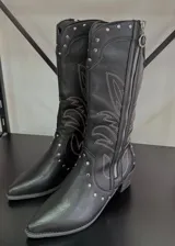 Botas texanas negras de caña alta con bordados en color blanco y tachas plateadas. Cierre lateral con cremallera.